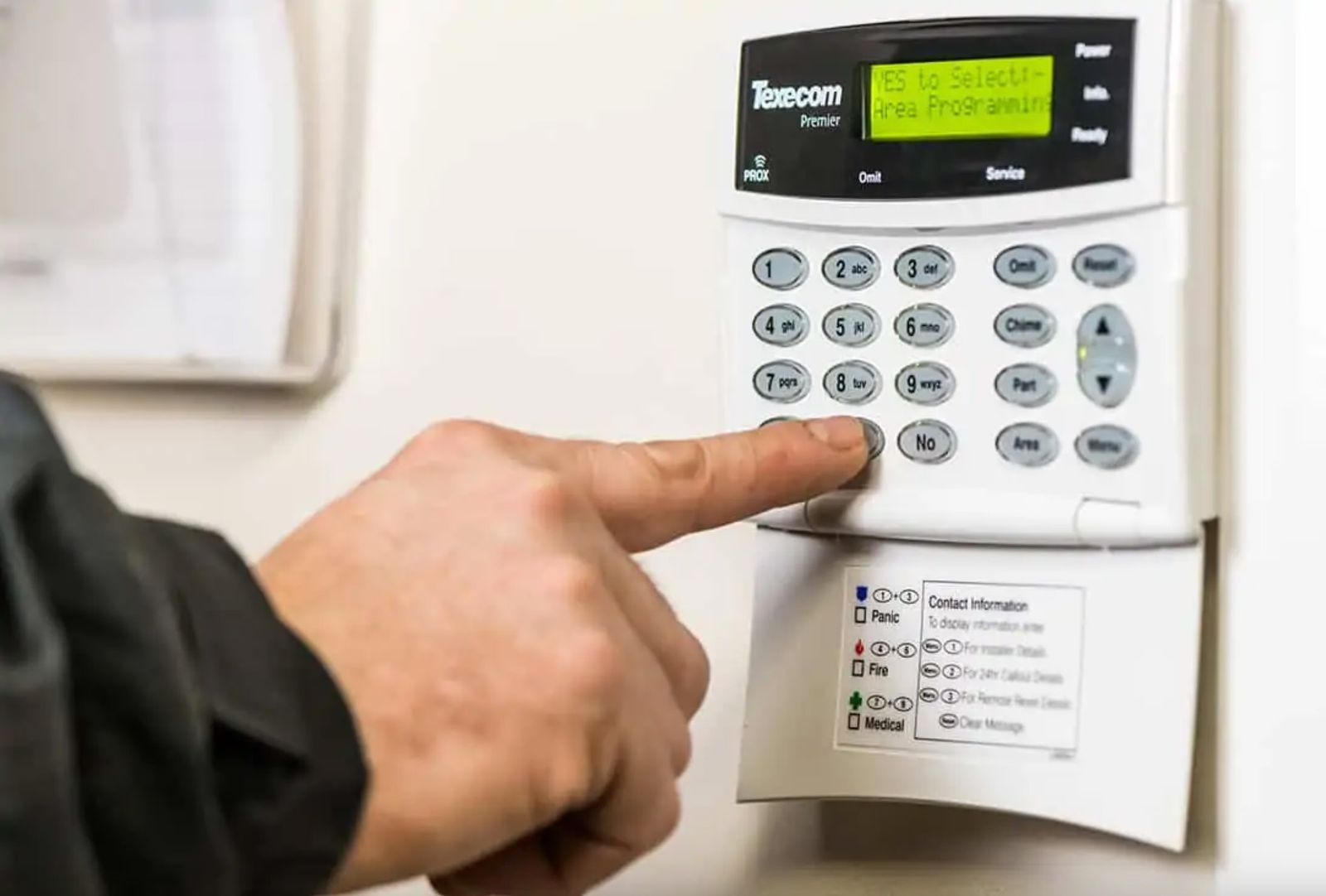 Hand entering a code on an alarm keypad